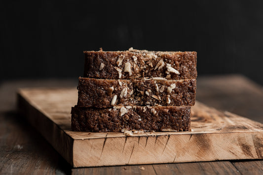 Three slices of dark bread stacked on a wooden board