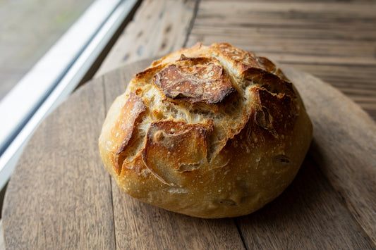 A round loaf of crusty bread on a wooden board