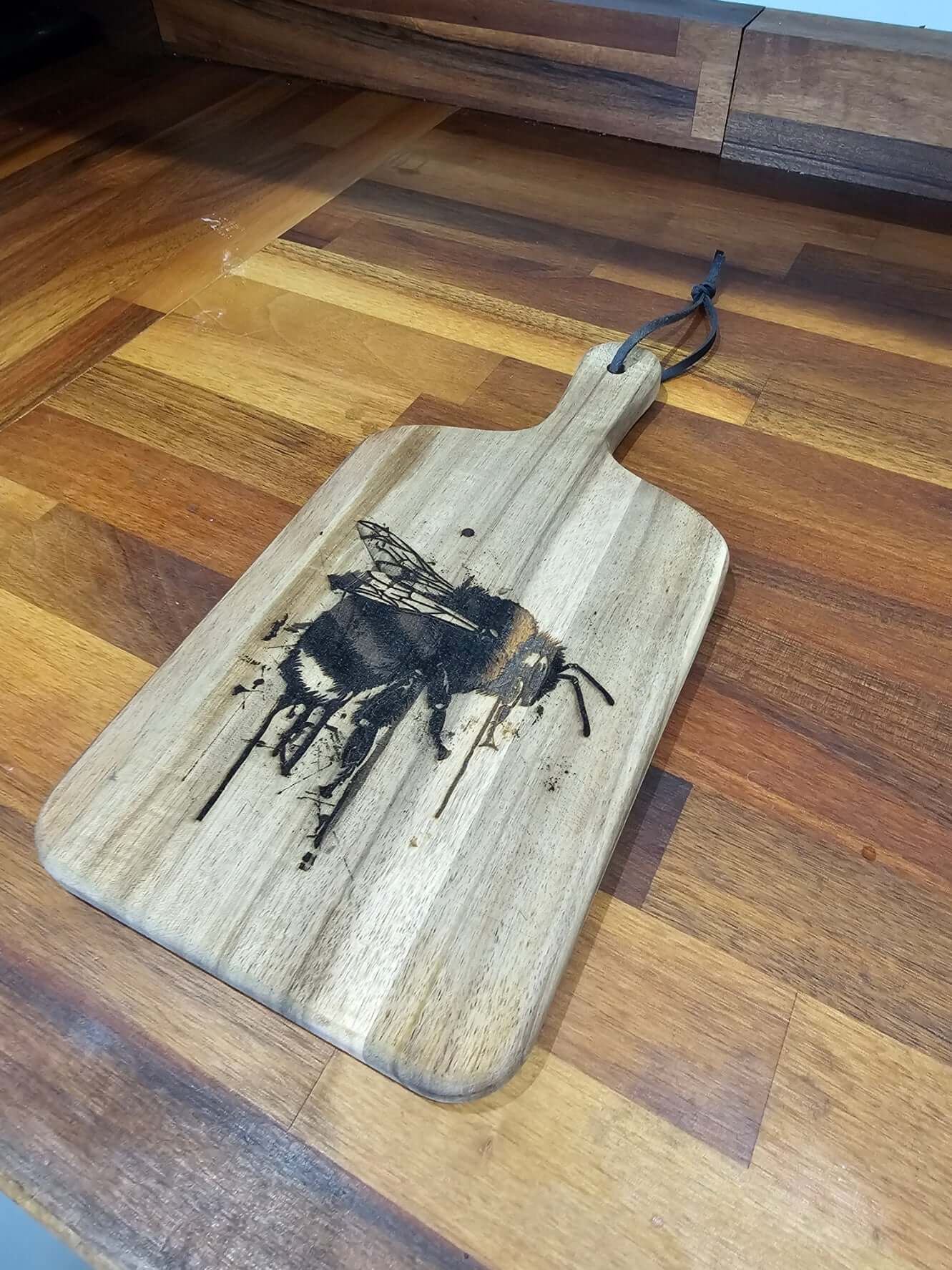 Handcrafted Engraved Bee Serving Board on a wooden counter, showcasing rustic design and bee engraving.