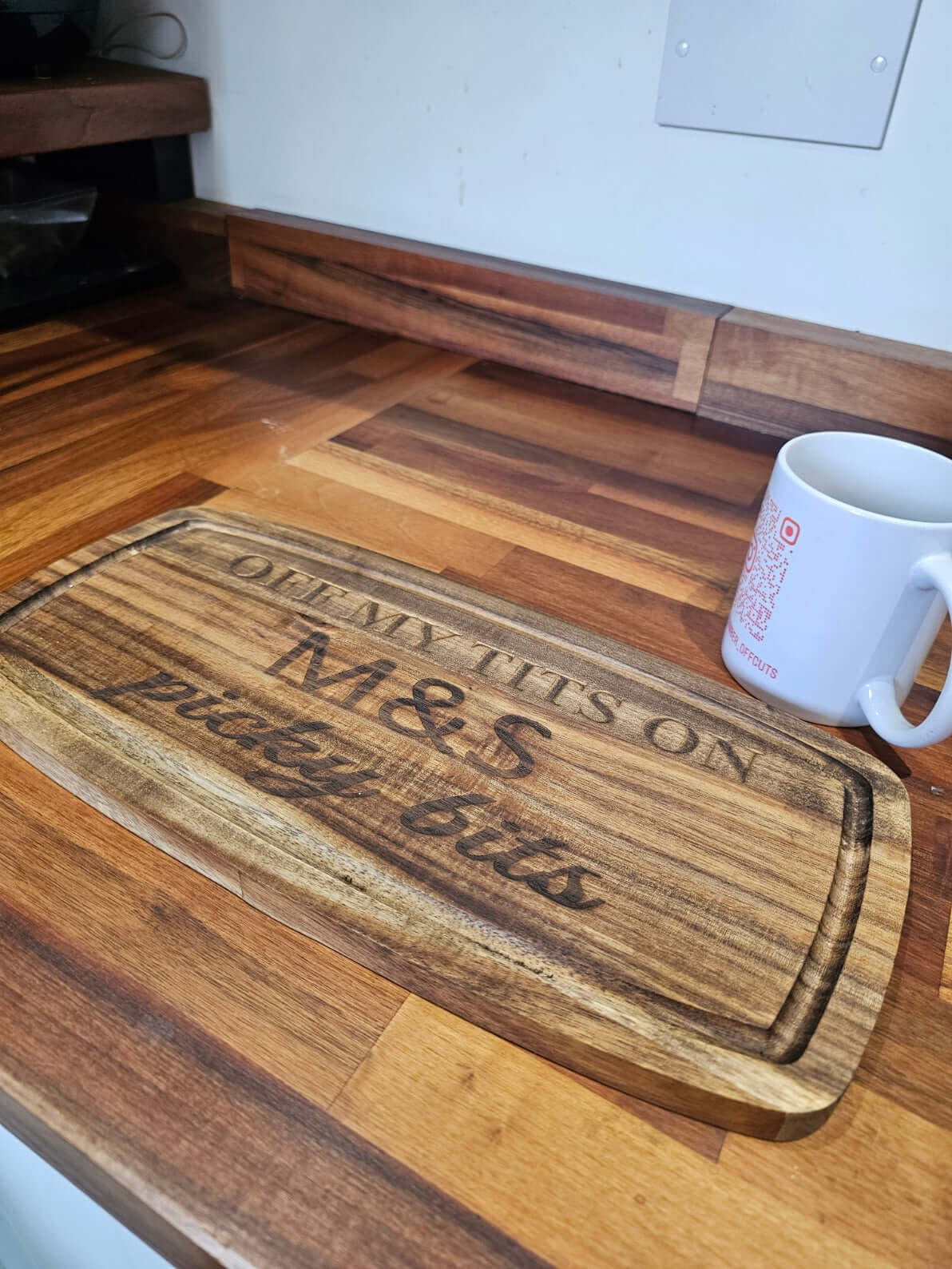 Funny Engraved Wooden Serving Tray with humorous text 'Off My Tits on M&S Picky Bits' on a wooden countertop.