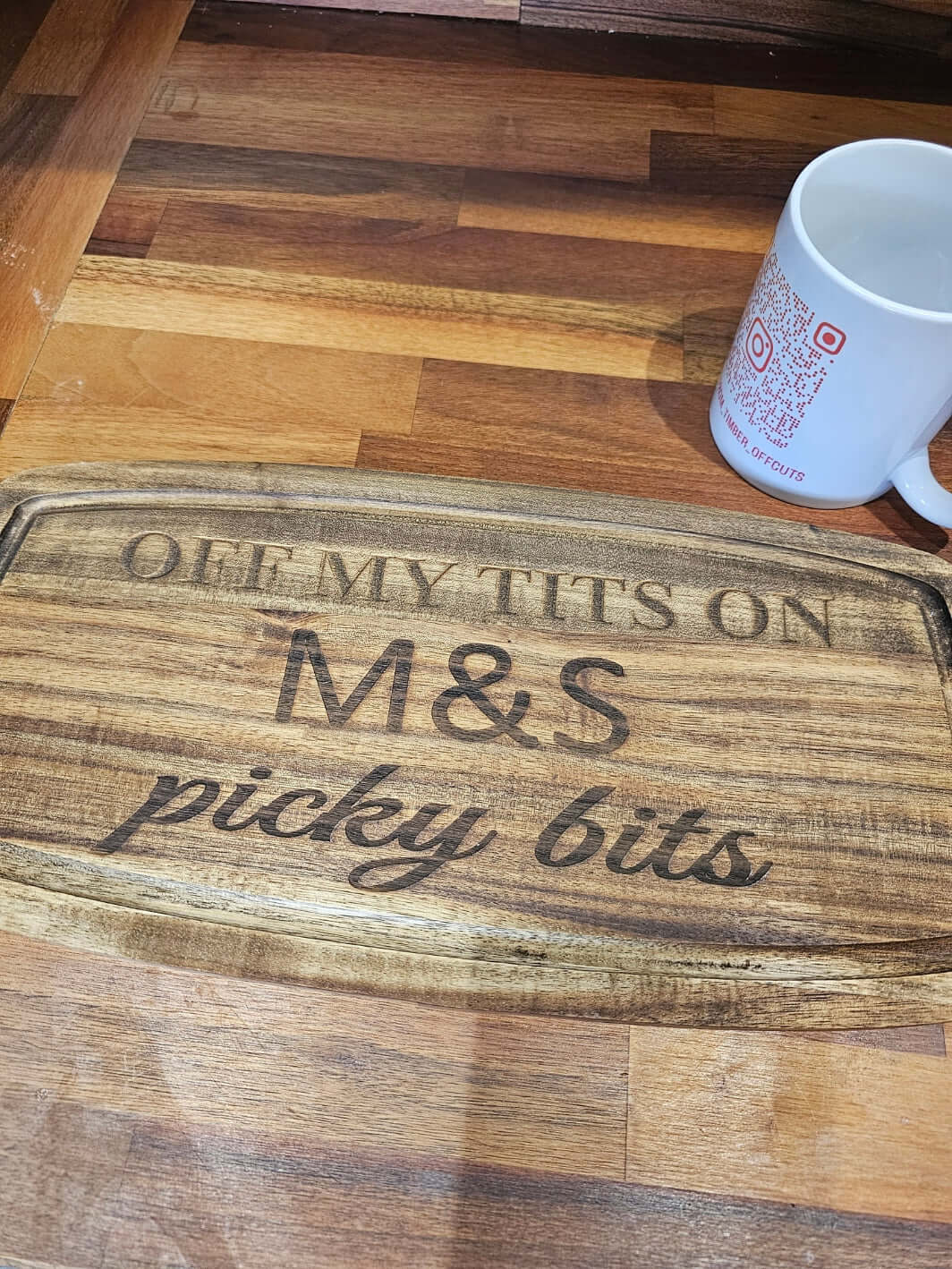 Funny Engraved Wooden Serving Tray with humorous text 'Off My Tits on M&S Picky Bits' on a wooden surface.