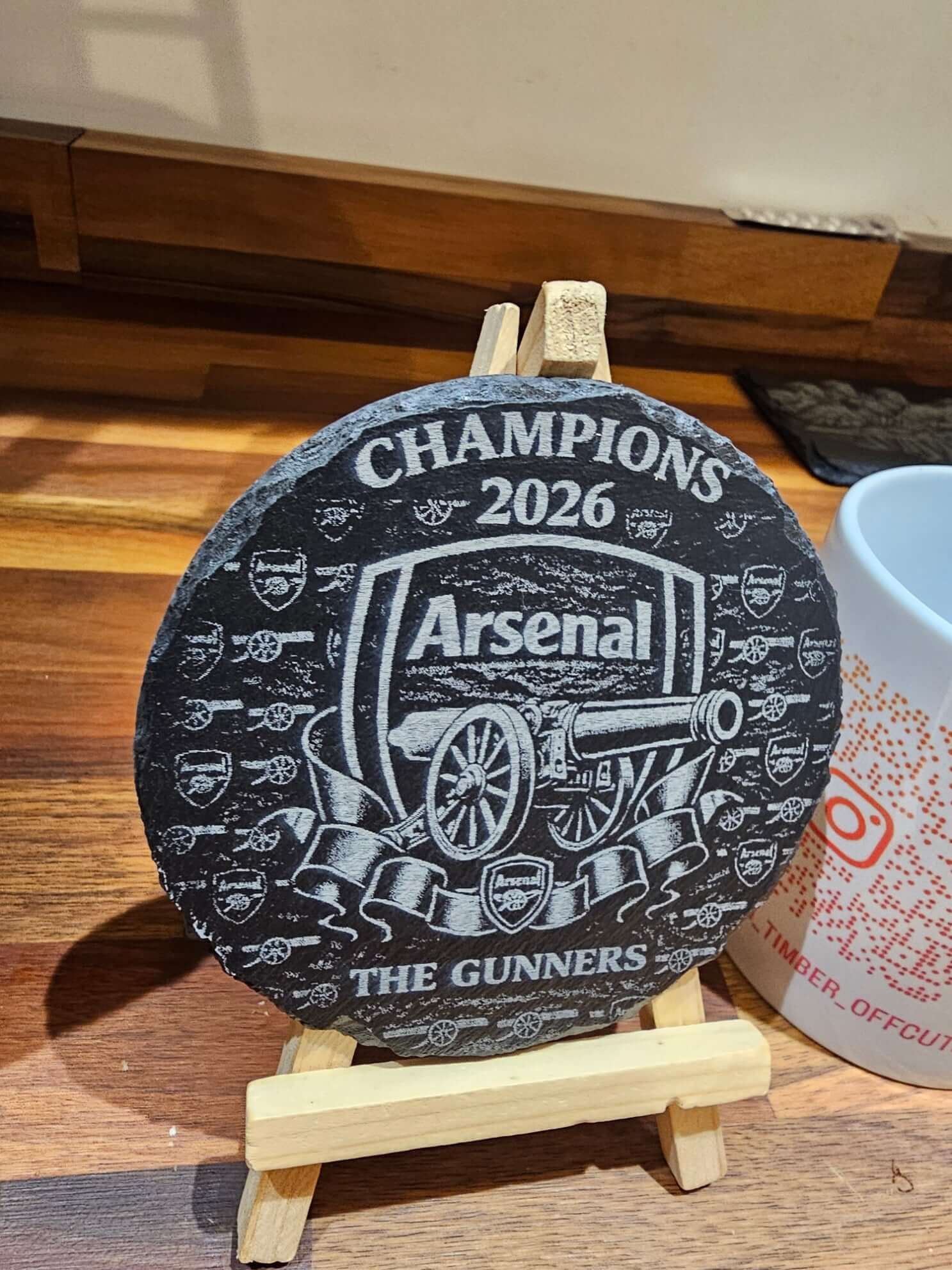 Arsenal Champions 2026 Engraved Slate Coaster – 10cm x 10cm Football displayed on a wooden stand.