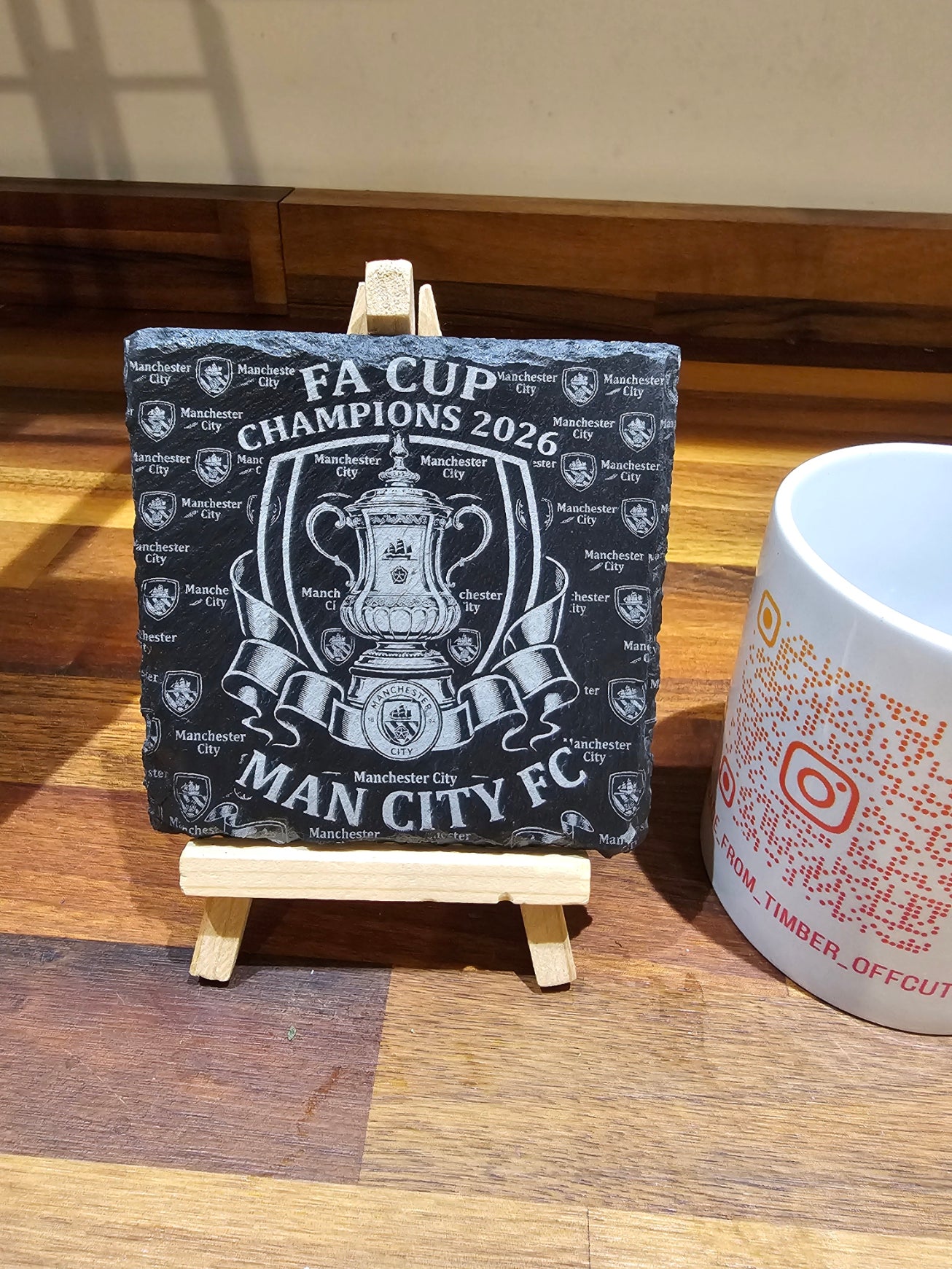 Manchester City FA Cup Champions 2026 Slate Coaster displayed on an easel with decorative design.