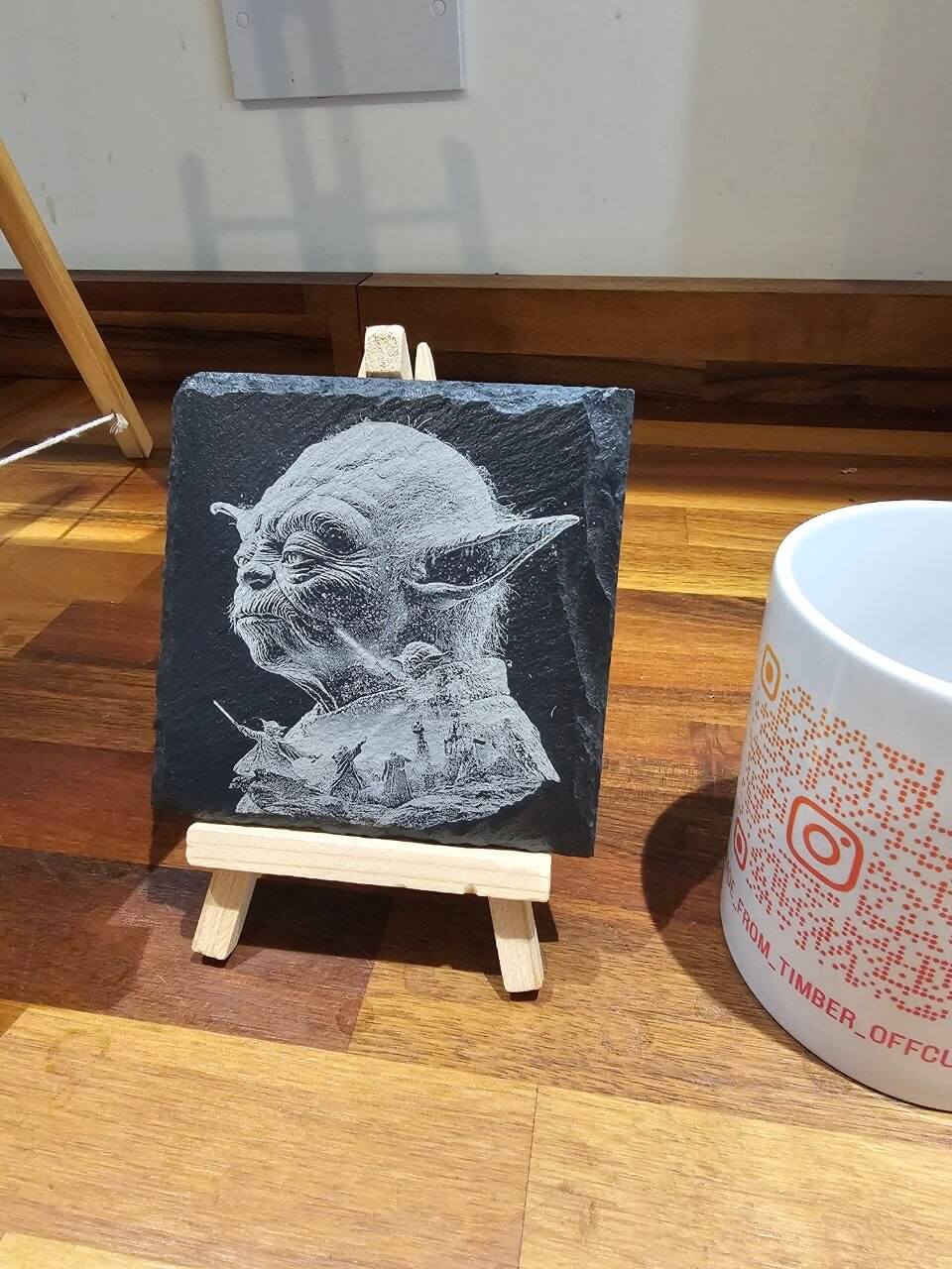 Slate Coasters Yoda laser Engraving displayed on an easel with a coffee mug in the background.