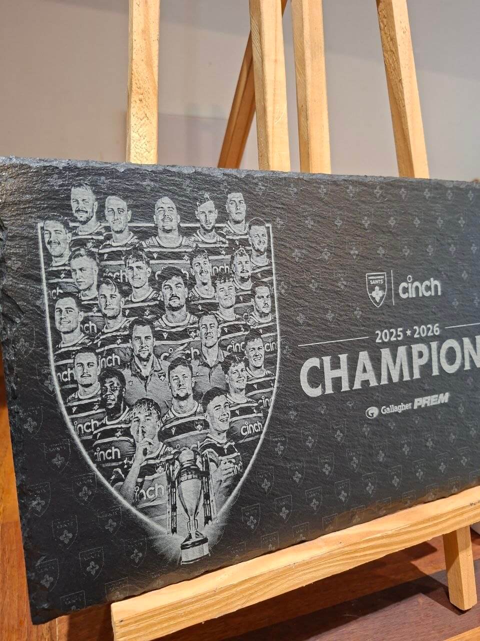 Northampton Saints Champions 2025 2026 Engraved Slate Plaque displayed on easel with team photo and trophy details.